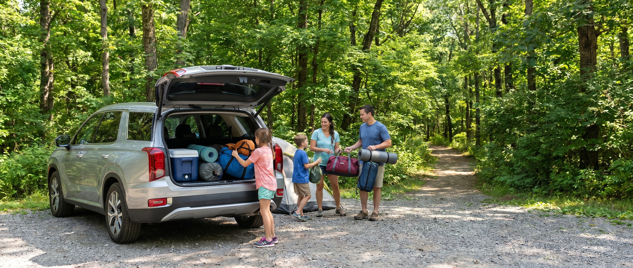 A family loading camping gear into the rear cargo area of a silver Hyundai Palisade at a Tennessee state park trailhead, surrounded by lush green trees and a gravel parking area on a sunny day.