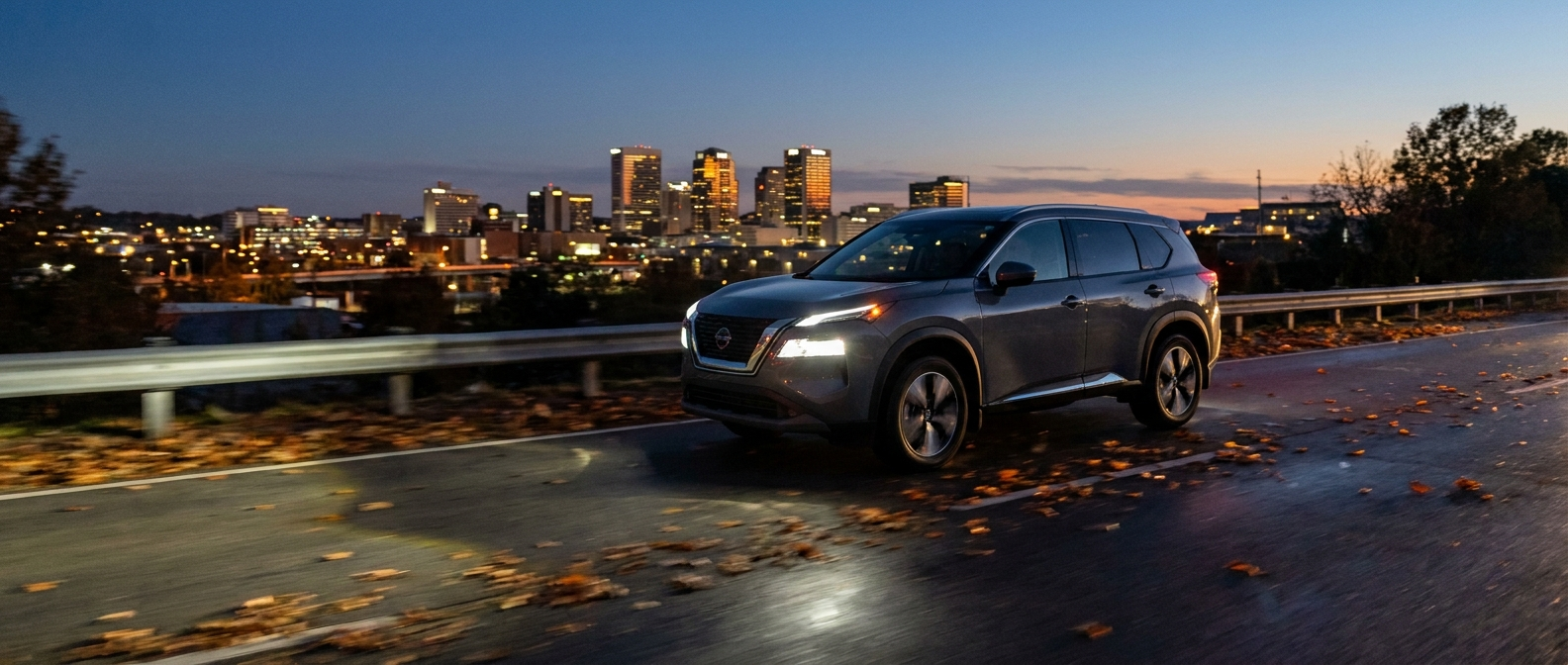2026 Nissan Rogue LED headlights on at dusk on a Birmingham Alabama highway in fall