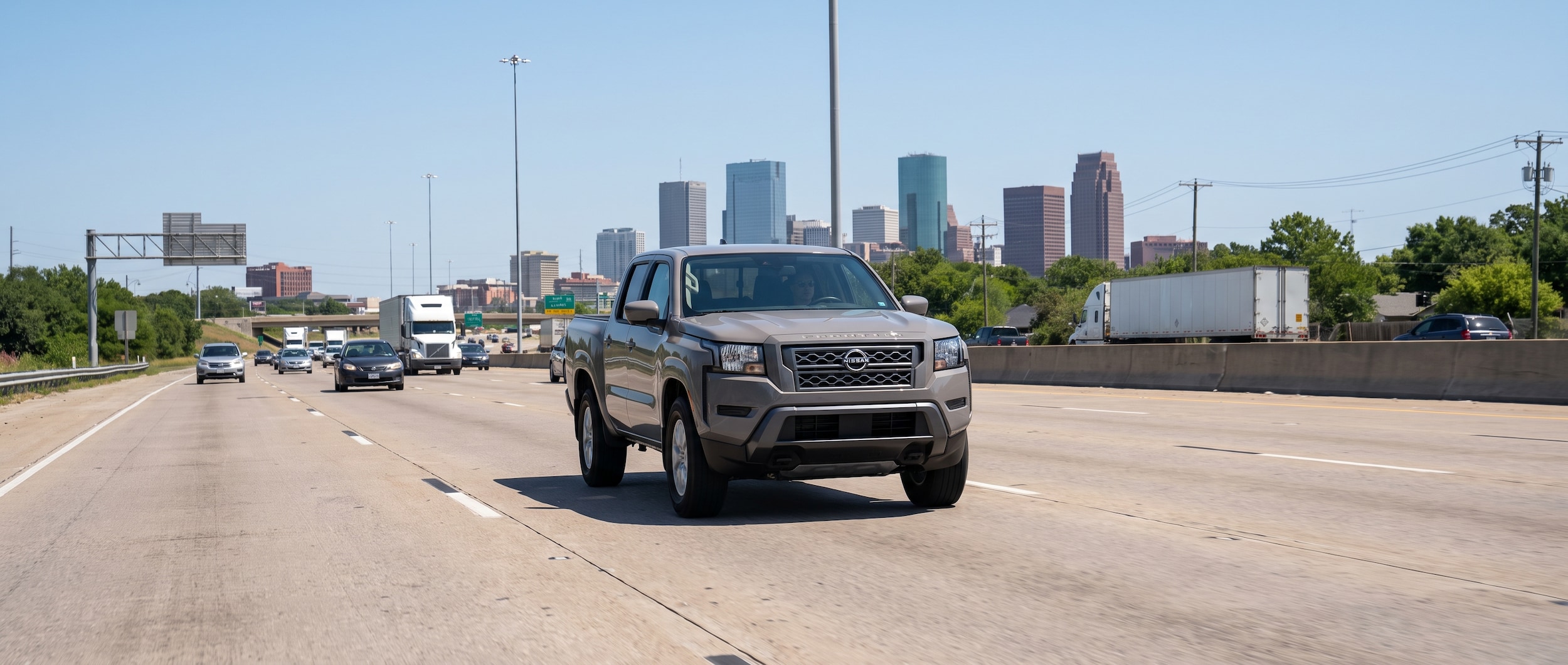 2026 Nissan Frontier driving north on I-65 toward downtown Birmingham, Alabama skyline in background
