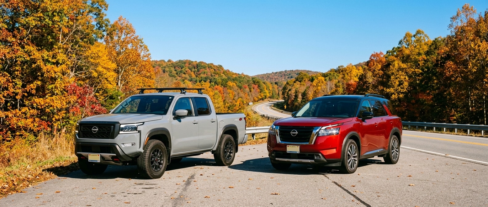 2026 Nissan Frontier and 2026 Nissan Pathfinder parked side by side on an Alabama highway surrounded by fall foliage