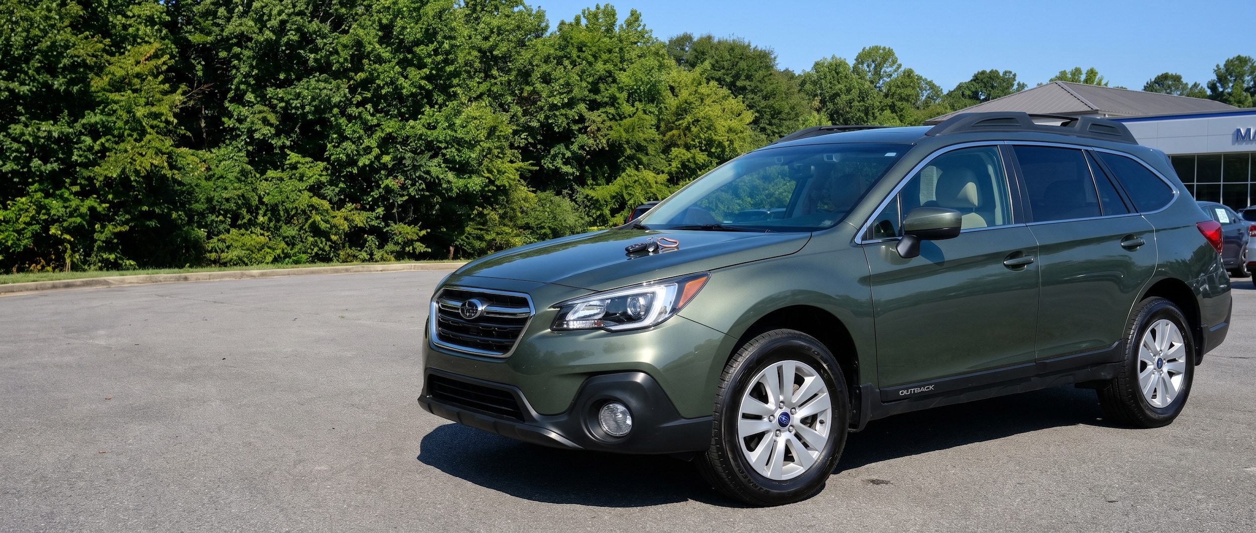 Subaru Outback on a Birmingham dealership lot, keys on hood, ready for trade-in appraisal at Hallmark Subaru Birmingham