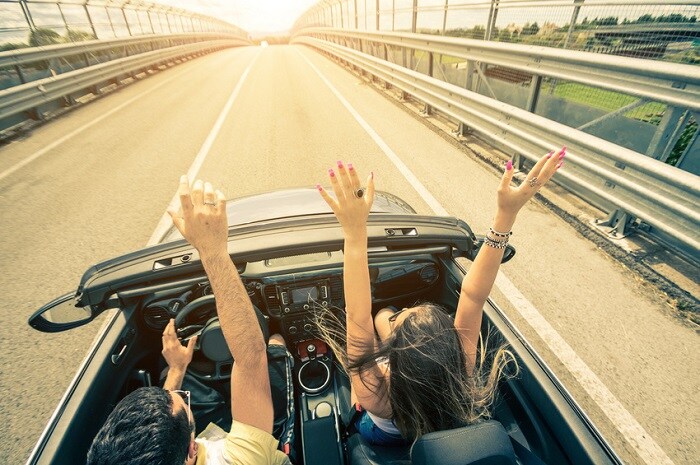 Couple_Driving_With_Hands_Up.jpg