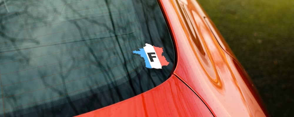 Sticker on car window depicting the country France as an outline, in French flag colors with an F in the middle