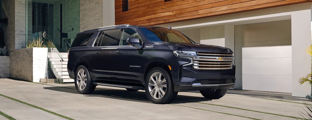 2022 Chevy Suburban black side view in front of a modern house_o