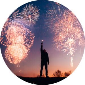Man Holding a Sparkler with Fireworks in the Background