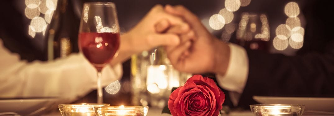 Couple Holding Hands at a Dinner Table with Wine and Roses