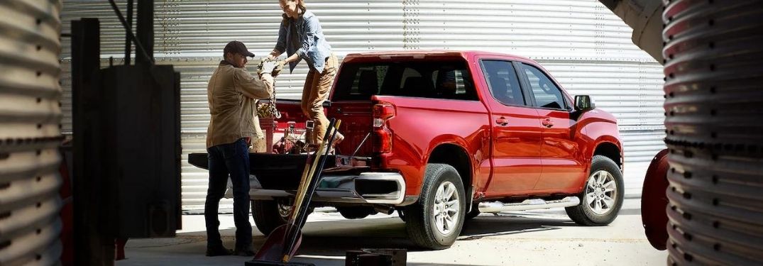 Man and Woman Loading Cargo in the Back of a Red Chevy Silverado