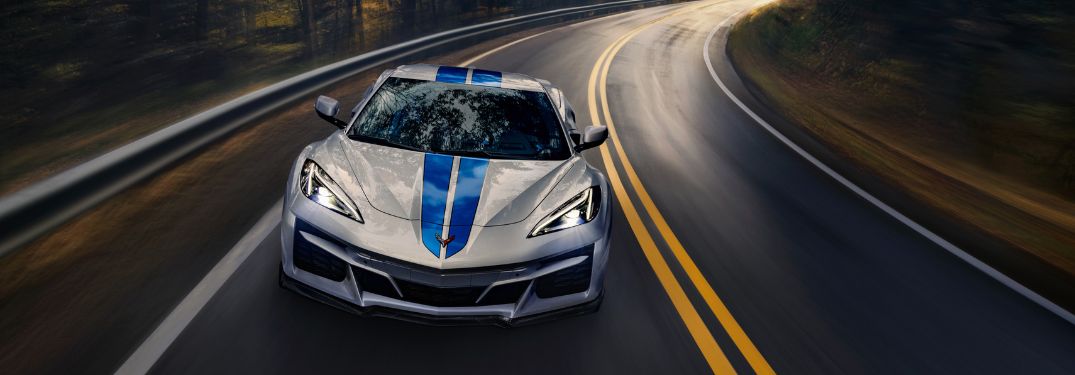 White 2024 Chevy Corvette E-Ray with Blue Racing Stripes on a Freeway