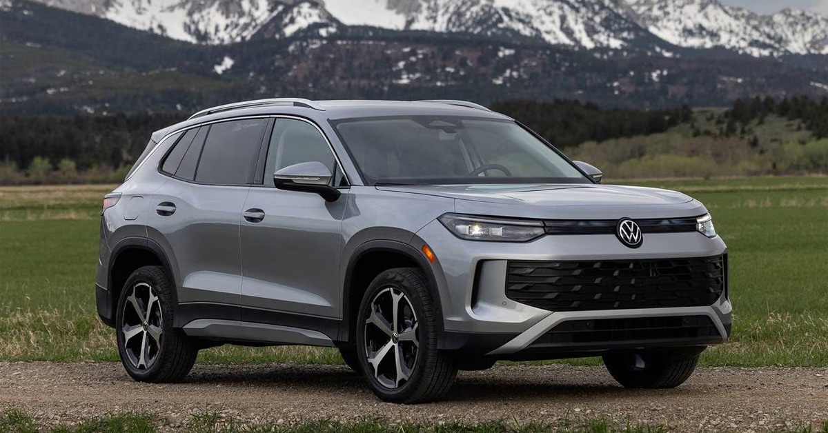 2026 Volkswagen Tiguan SUV parked in a scenic field with snow-capped mountains in the background.