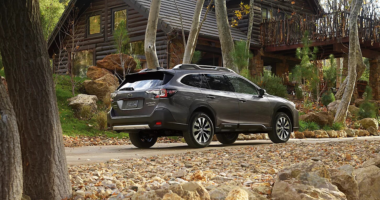 A 2025 Subaru Outback parked outside a cabin in the
woods. 
