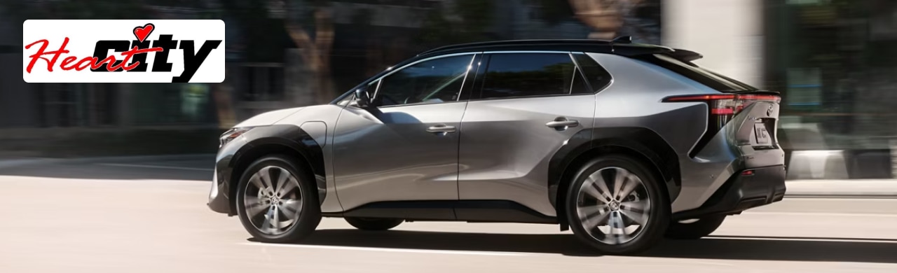 A silver Toyota bZ4X SUV driving on a city street.