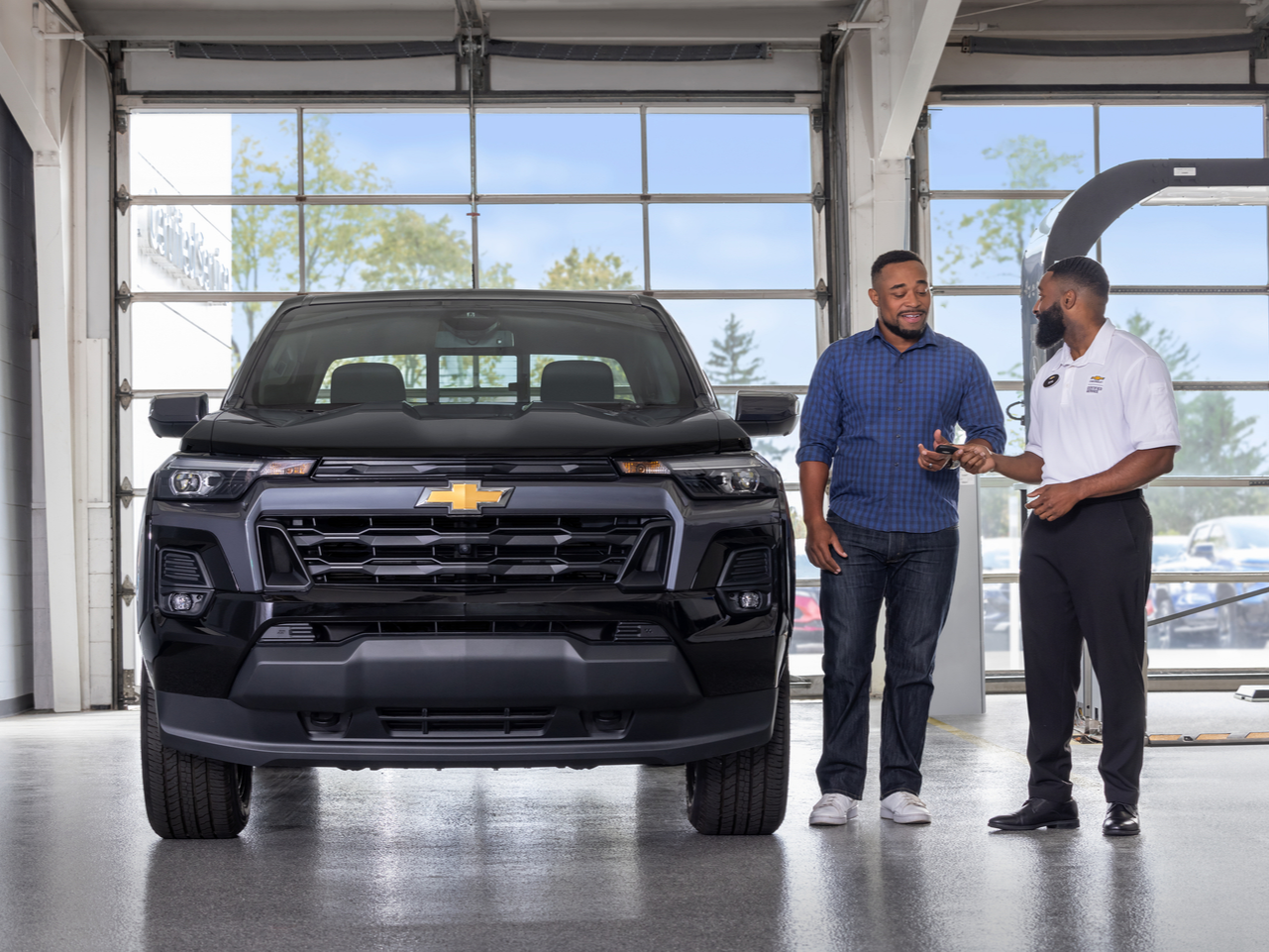 Chevrolet Sales staff and client talking next to a black Chevrolet vehicle