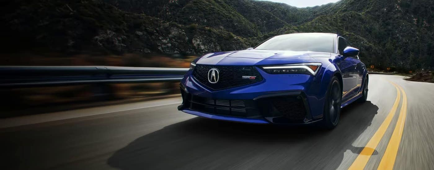 Blue 2026 Acura Integra driving on a winding road