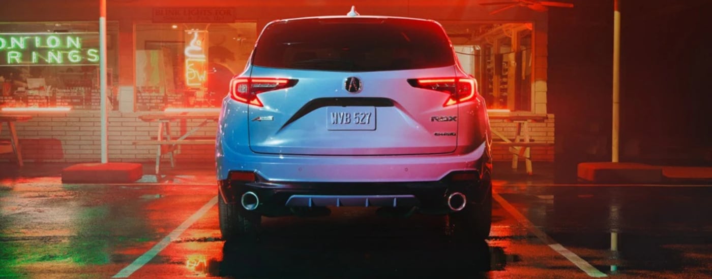 The rear of a white 2026 Acura RDX parked under neon lights