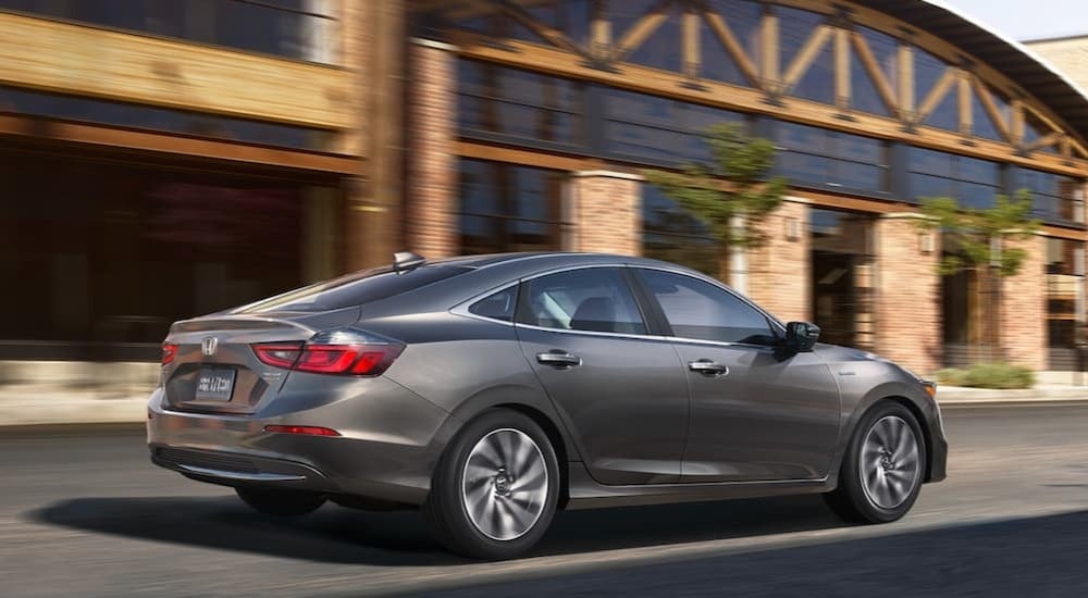 A grey 2022 Honda Insight Touring is shown driving past a building.
