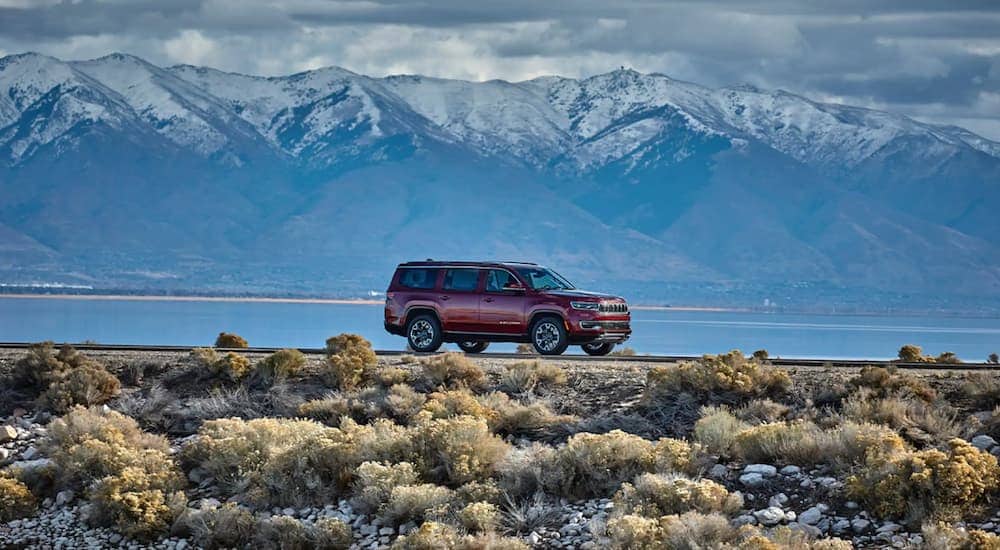A red 2022 Jeep Wagoneer is shown parked near a lake and a mountain.