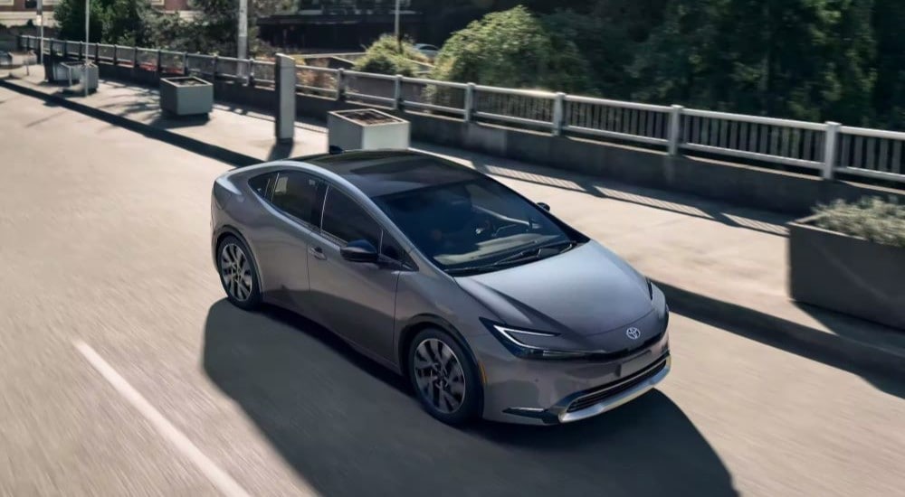 A grey 2023 Toyota Prius Prime XSE Premium is shown driving over a bridge after leaving a car dealership near Raleigh, NC.