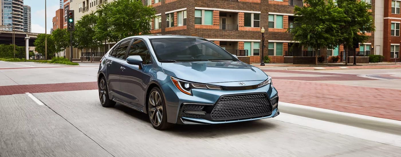 A blue 2022 Toyota Corolla XSE is shown driving on a city street after visiting a used car dealership near Raleigh.