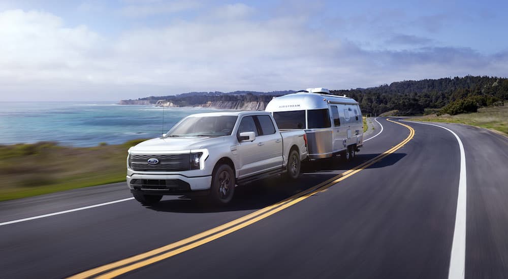 A white 2023 Ford F-150 Lightning is shown from the front at an angle.