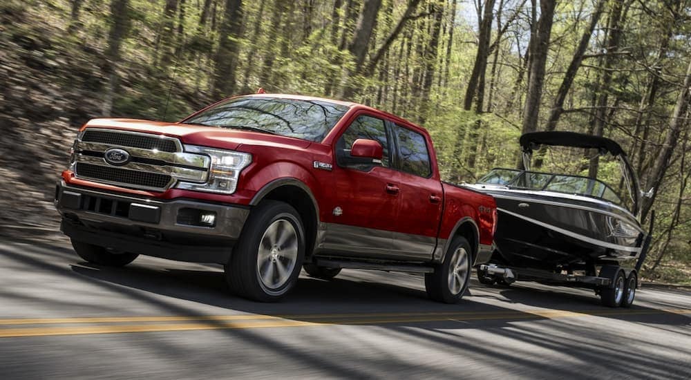 A red 2020 Ford F-150 is shown towing a boat.