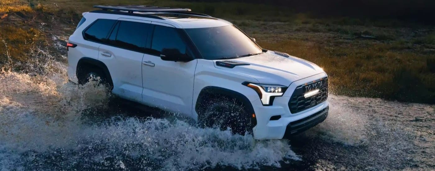 A white 2024 Toyota Sequoia TRD Pro is shown splashing through a creek.