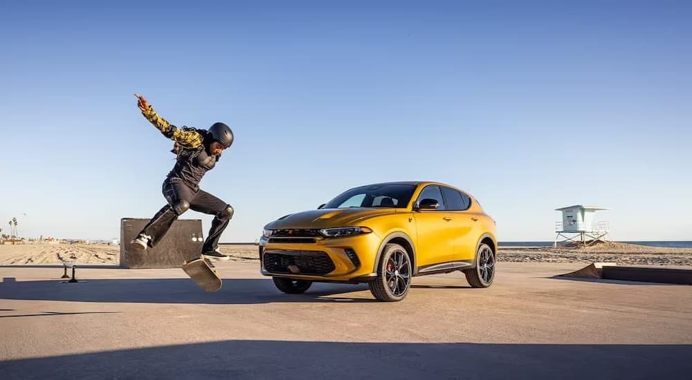 A yellow 2024 Dodge Hornet parked near a skateboarder.