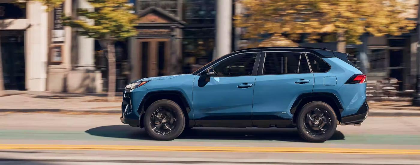 A side view of a blue 2023 Toyota RAV4 Hybrid XSE while driving.