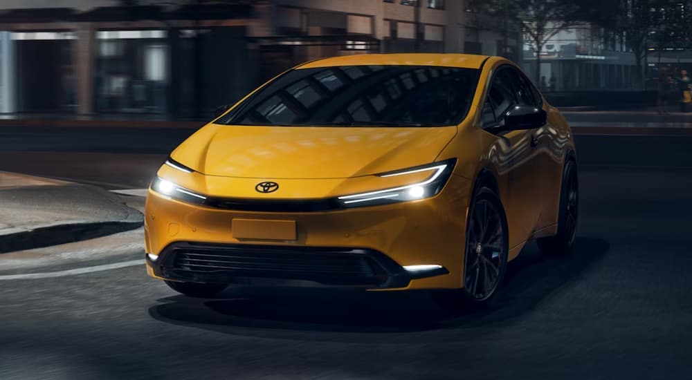 Yellow 2026 Toyota Prius driving down a city street.