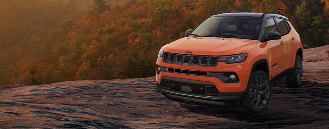An orange 2025 Jeep Compass from the front at an angle.