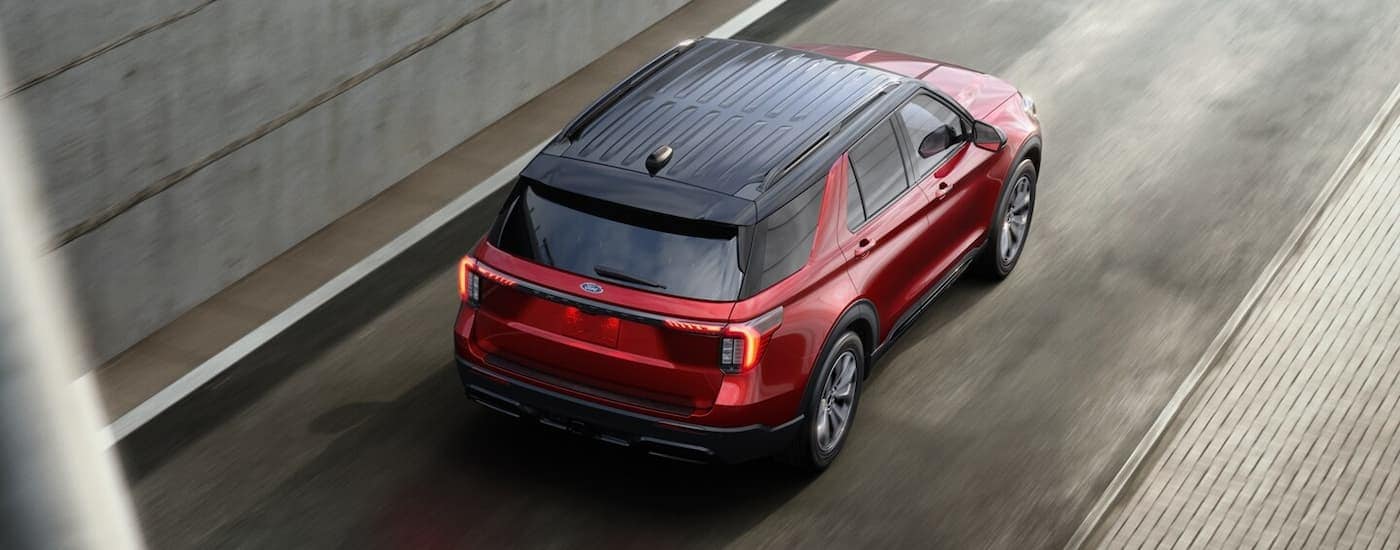 A red 2025 Ford Explorer is driving up a highway ramp.