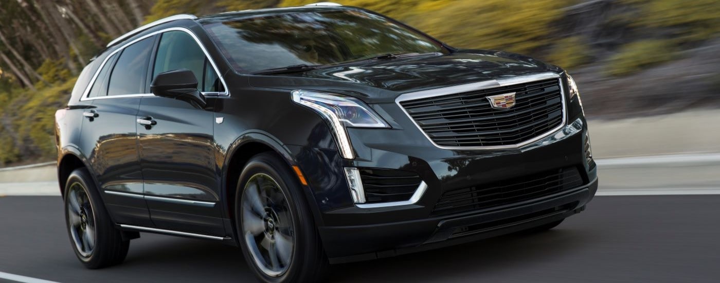 A black 2019 Cadillac XT5 Sport is driving on an open road after viewing used cards for sale.