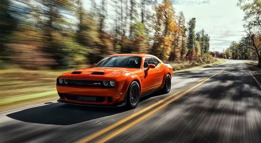 Orange 2025 Dodge Challenger SRT driving down a road.
