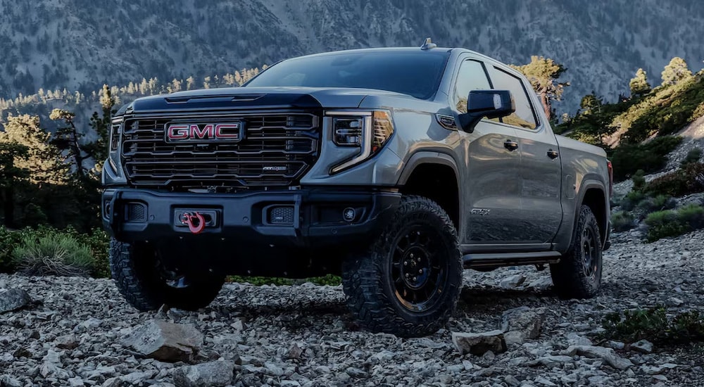 A grey 2024 GMC Sierra 1500 AT4X parked off-road on a rocky mountain.