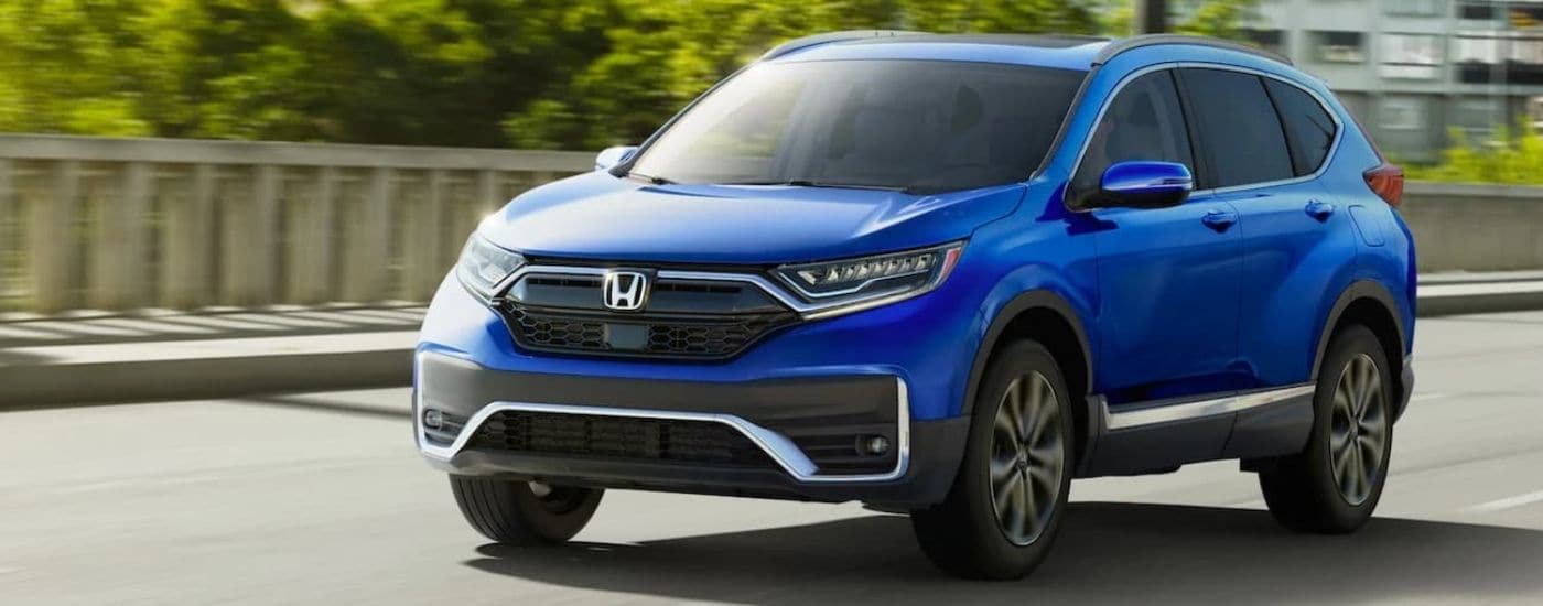 A blue 2021 Honda CR-V Touring driving to view used cars for sale in Charleston.