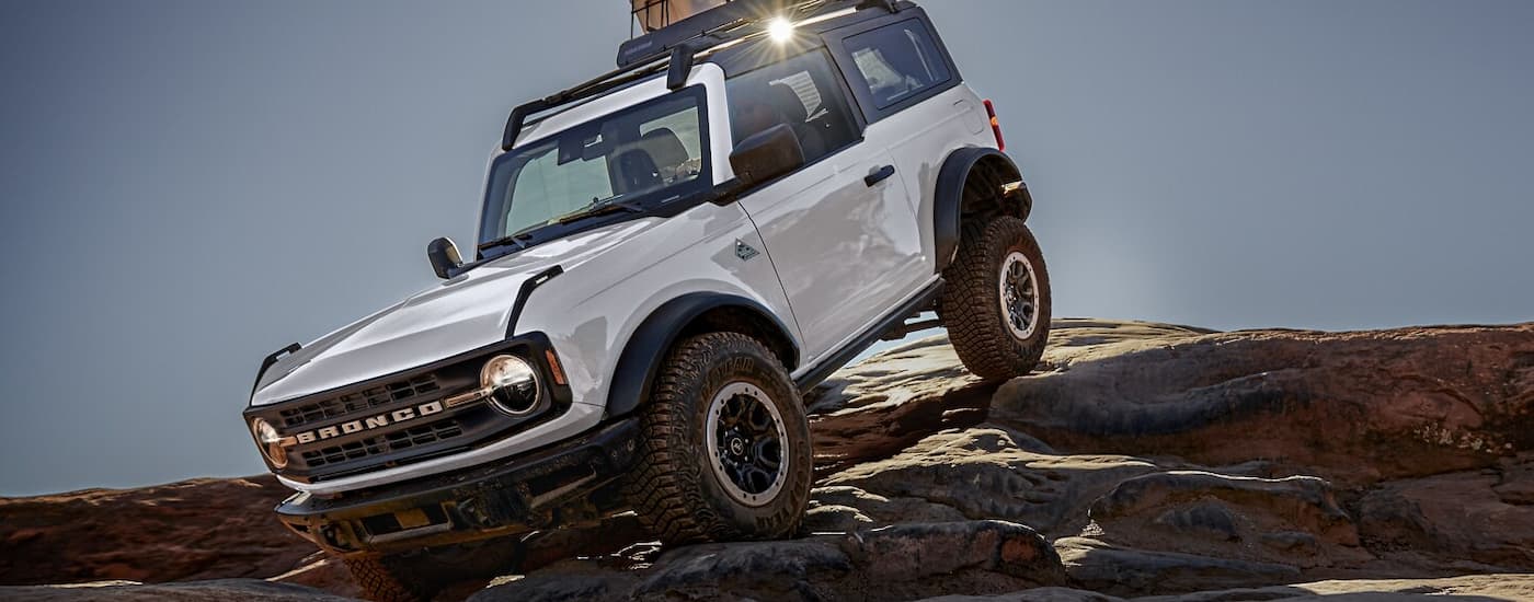 A white 2024 Ford Bronco is off-roading after visiting an auto dealer.