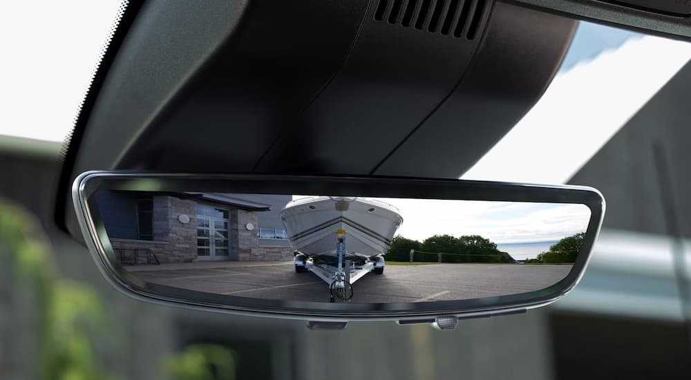 Close-up of the rear-vew mirror camera showing a boat being towed behind a 2024 Chevy Silverado HD.