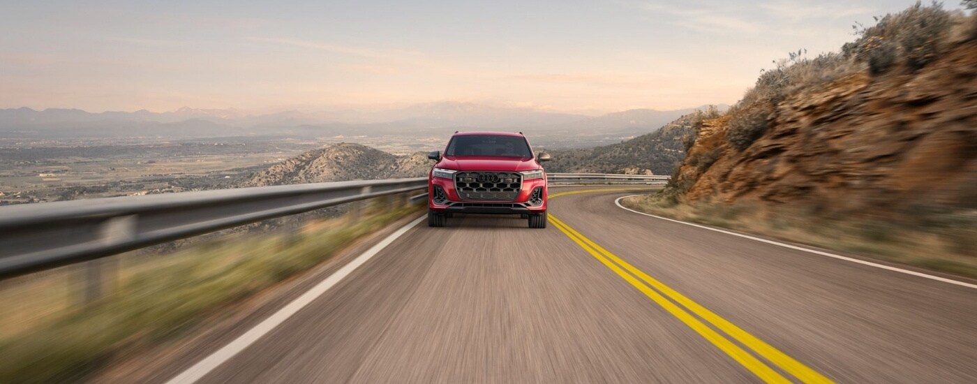 Red 2026 Audi Q7 driving on a winding highway