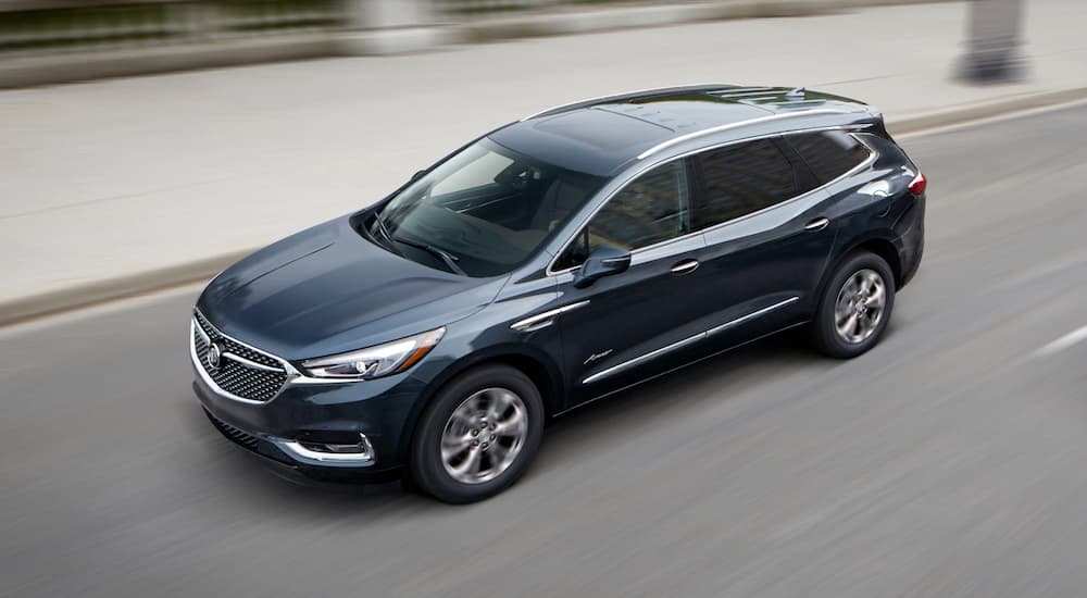 A blue 2019 Buick Enclave Avenir is shown driving on a city street.