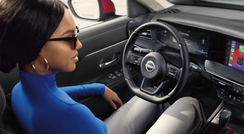 Woman in the driver's seat of a 2025 Nissan Kicks for sale near Boiling Spring Lakes
