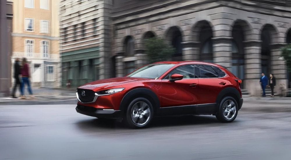 A red 2024 Mazda CX-30 driving in a city.