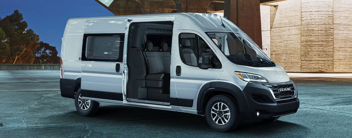A white 2024 Ram ProMaster Crew Van parked with the side door open.