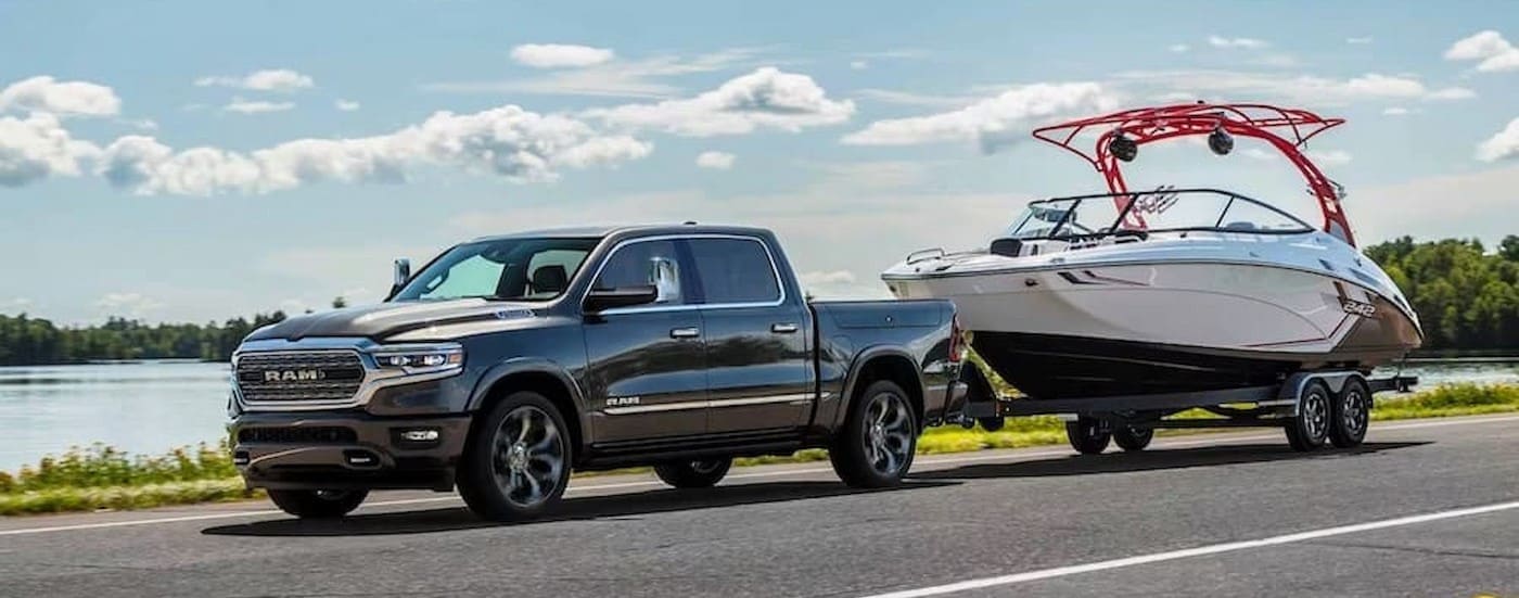 A black 2024 Ram 1500 is shown towing a boat.