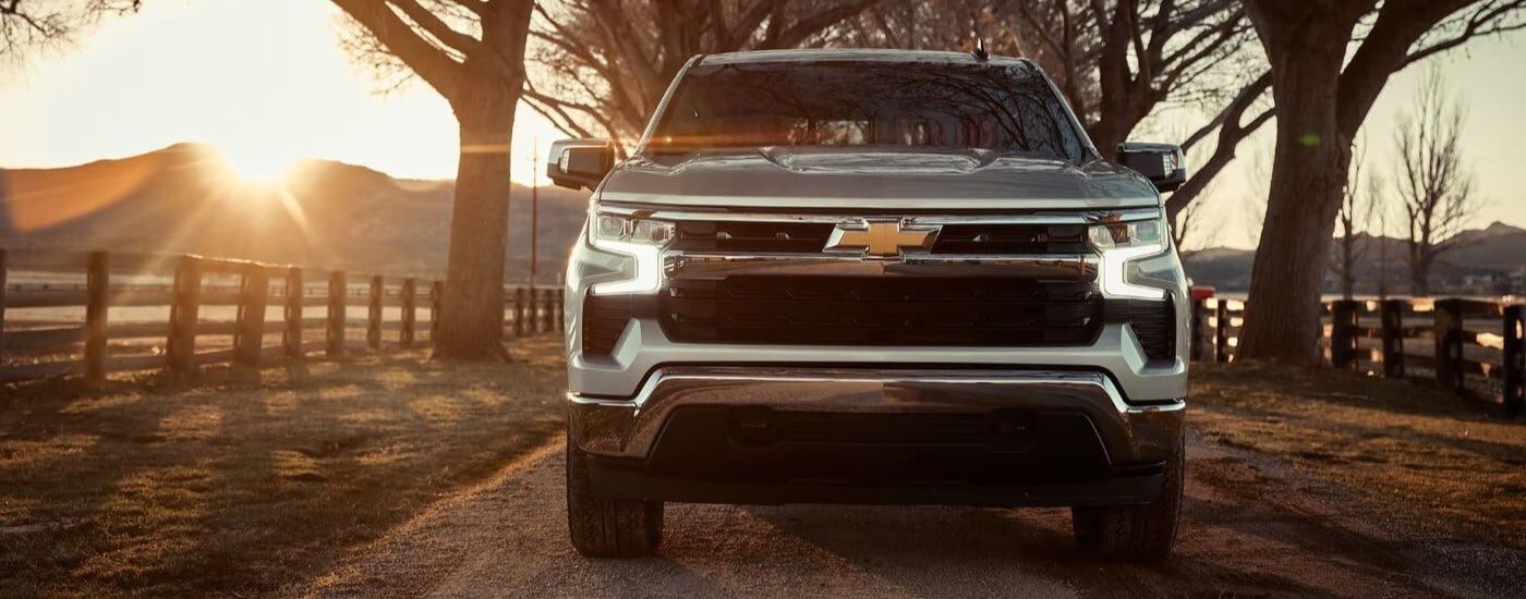 Front angle view of a silver 2023 Chevy Silverado 1500 driving from a truck dealership near Atlanta.