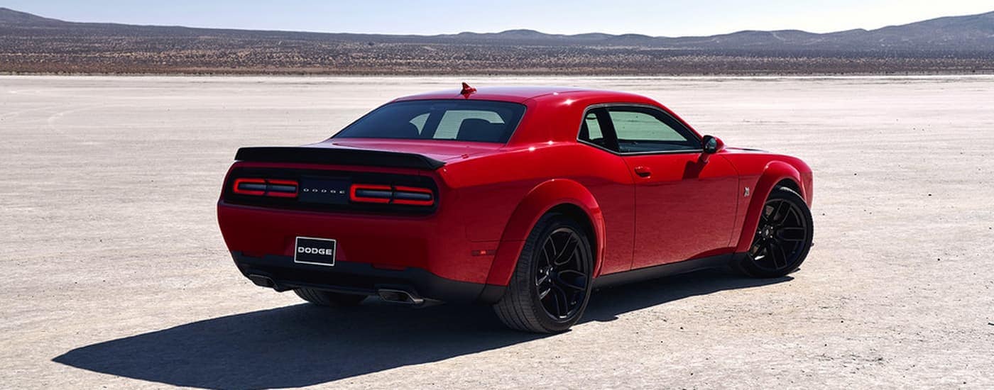 Red 2021 Dodge Challenger parked in an open dirt lot.