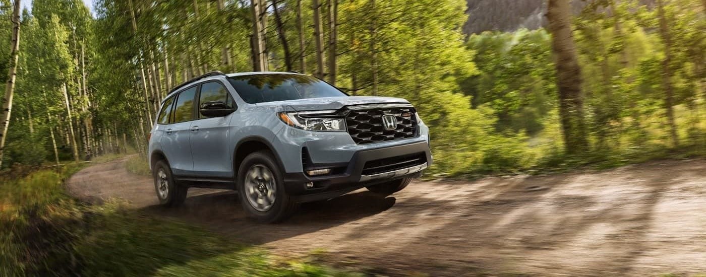A grey 2024 Honda Passport TrailSport driving through a forest.