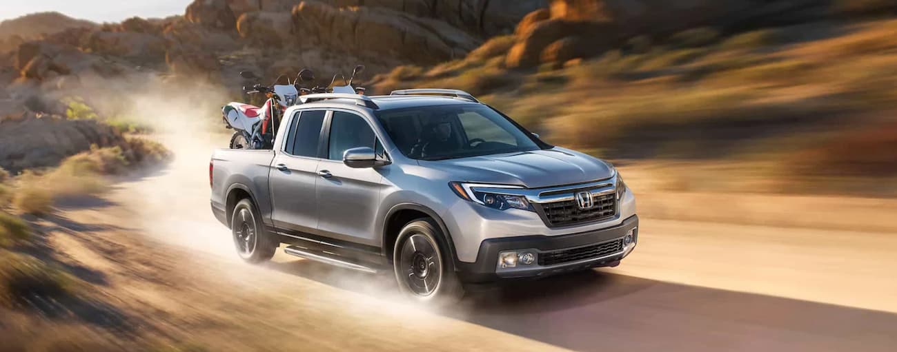 A silver 2020 Honda Ridgeline RTL-E driving on a dirt road.