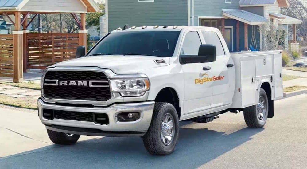 A white 2024 Ram 2500 Chassis Cab is shown parked near a house.