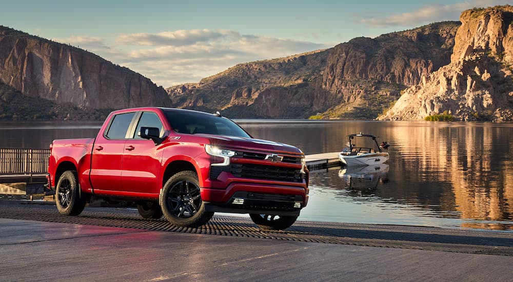 A red 2024 Chevy Silverado 1500 RST is parked near a lake.