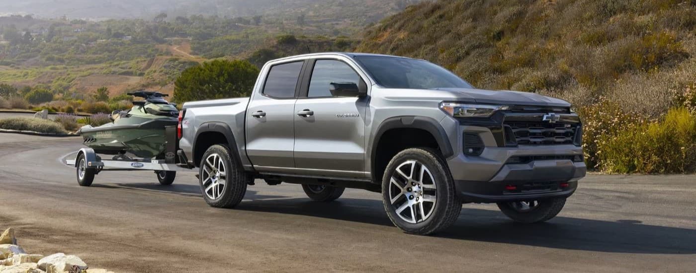 Grey 2023 Chevy Colorado Z71 towing a jetski down a road.