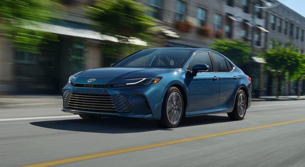 A blue 2025 Toyota Camry driving in a city.